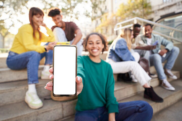 smily girl showing smartphone with empty screen at street city with friends. carefree young millenni