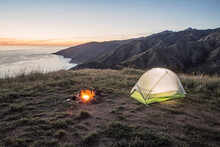 A Campsite With A Campfire Overlooks The Pacific Ocean At Sunset, Big Sur, California.
