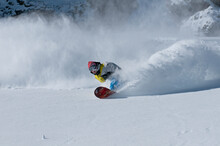 A Male Snowboarder Makes A Series Of Deep Powder Turns While Snowboarding At A Mountain Resort