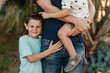 © Cavan Images - Mid view of elementary age boy hugging father and brother and smiling