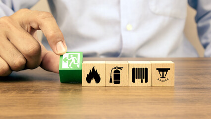 Wall Mural - Hand choose cube wooden toy block stack with door exit sing or fire escape with fire prevent icon and fire extinguisher and emergency prevention or protection symbol for safety and rescue.