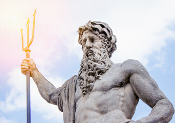 Wall Mural - A statue of Neptune in a sunbeam on a blue sky background. Greek mythology