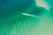 Aerial Looking Down On Power Boat And Wake In Shallow Green Water And Sand Ripples.