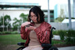 © Austockphoto - Woman with a disability sitting in a wheelchair looking down at her mobile phone