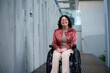 © Austockphoto - Smiling woman with a disability sitting in a wheelchair outside in urban setting