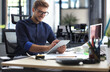 © ty - Young modern business man working using digital tablet while sitting in the office.