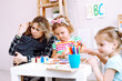 © Татьяна Волкова - Young educator embrace and calm down crying boy in kindergarten. Pretty little girls with interest playing with educational toys on desk. Fail, support, hugs, lesson in daycare centre
