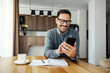 © Dusan Petkovic - A happy casual businessman is texting messages on the phone while working from home.