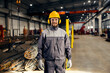A metallurgy worker in protective uniform is standing in facility ready for labor.
