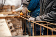 Cropped picture of workers working with wire and pliers and making foundation on construction site.