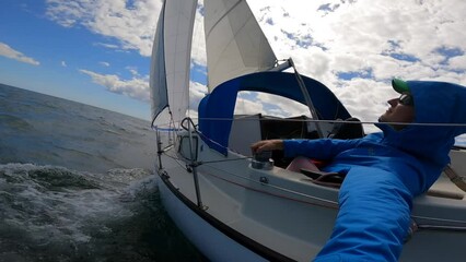 Wall Mural - Young sailor recording selfie from Sailboat in wavy, open sea. Travel, adventure concept