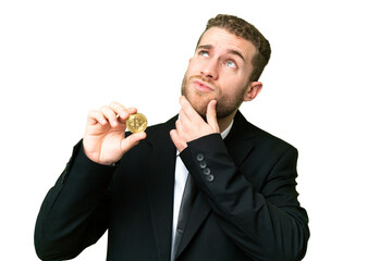 Young business blonde man holding a Bitcoin over isolated chroma key background having doubts