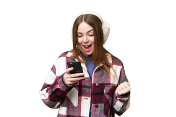 Sticker - Young pretty woman wearing winter muffs over isolated chroma key background surprised and sending a message