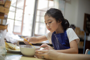 Asian Mother and daughter are cooking food and having fun in the kitchen.