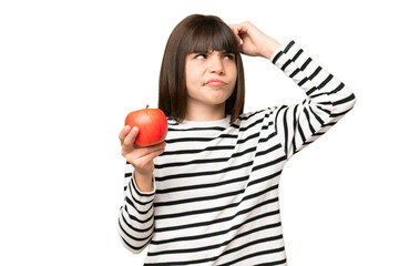 Wall Mural - Little girl with an apple over isolated chroma key background having doubts and with confuse face expression