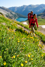 A Mother Carries Her Child In Her Backpack Through A Meadow Over Trail Rider Pass By Snowmass Lake During A Multiday Backpacking Trip In The Maroon Bells In Snowmass Wilderness Jus