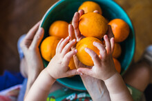 A Mother And Son Place Organic Oranges In A Green Bowl.