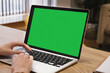 © Galina - Green screen, copyspace and chromakey on a laptop of a business person typing. Laptop on the desk in the office. Template for inserting an image on the laptop screen.