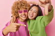 © wayhome.studio  - Best female friends have fun make frame gesture with fingers smile toothily wear casual jumpers foolish around isolated over pink background. Happy biracial women measure angle picture something