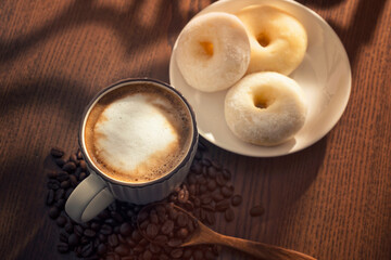 Wall Mural - Hot latte and donuts on wooden table behind window