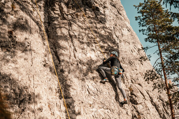 Wall Mural - Climber wearing in climbing equipment. Practicing rock-climbing on a rock  mountain wall. Climbing sports and bouldering concept. rock climber climbs on a rocky wall.