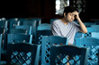 © anut21ng Stock - Asian man with headache, stress, sitting alone in a room with many chairs.