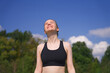 © Евгений Шемякин - Happy positive fit fitness girl, joyful young woman is enjoying sun, good summer weather, sunbathing at sunny day on natural green and sky background.