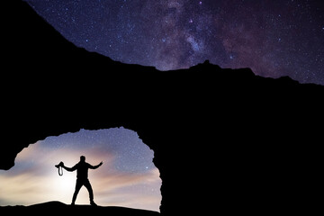Wall Mural - Hiker silhouette stands  on the rock, behind them fantastic beautiful night sky with milky way galaxy. 