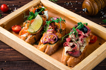 Canvas Print - Assorted bruschetta with salmon, beef cut, sun-dried tomatoes, onion, mushrooms, cream cheese and baguette.