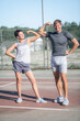 © Sergei - Athletic couple checking their muscles Strong biceps, doing sport exercises, training together outdoor on sport ground.