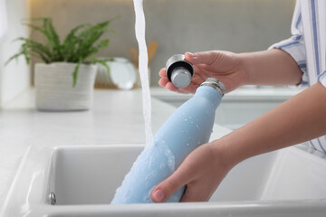 Canvas Print - Woman washing thermo bottle in kitchen, closeup