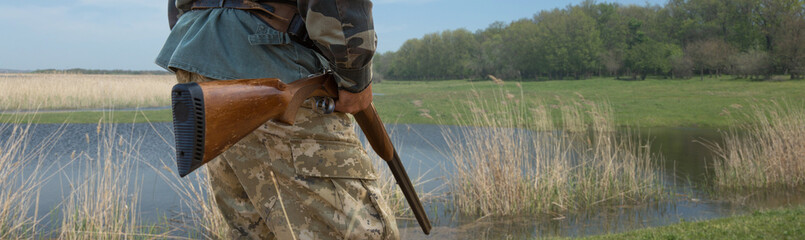 Wall Mural - Hunter man in camouflage with a gun during the hunt in search of wild birds or game.