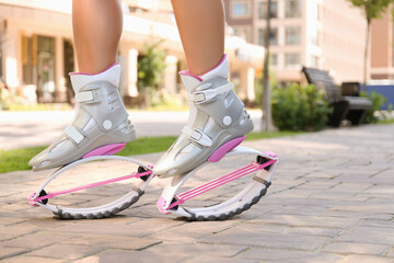 Wall Mural - Girl in kangoo jumping boots on city street, closeup