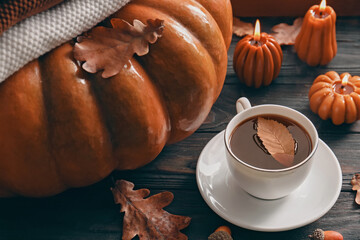 Wall Mural - Cup of hot drink and pumpkin shaped candles on wooden table. Cozy autumn atmosphere