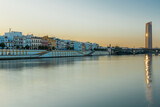 Fototapeta Londyn - Sunset over the authentic neighborhood of Tirana in Seville with views on Calle Betis, Torre Sevilla and with awesome reflections in the river Guadalquivir, creating magic atmosphere and views