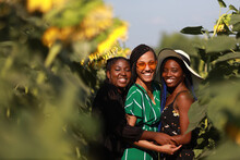 Three Young Cheerful Women In A Field With Sunflowers In Summer