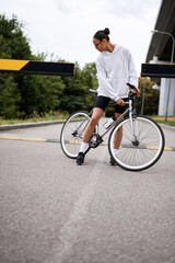 Sticker - Stylish african american cyclist in sunglasses looking at bike near barrier on road 