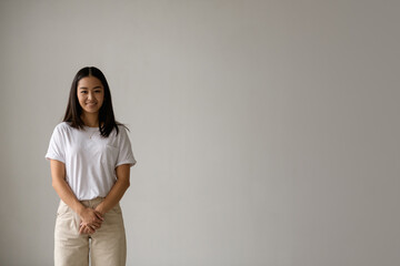 Brunette young asian woman smiling at camera isolated on grey with copy space 