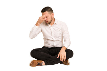 Wall Mural - Adult latin man sitting on the floor cut out isolated having a head ache, touching front of the face.