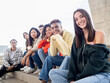 © gonzagon - Diverse teenage friends looking at camera smiling sitting on stairs in a city