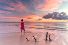 Woman On Tropical Beach Looks At Caribbean Sea At Sunset