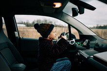 Young Boy Sat In The Drivers Seat Of An Electric Car Playing