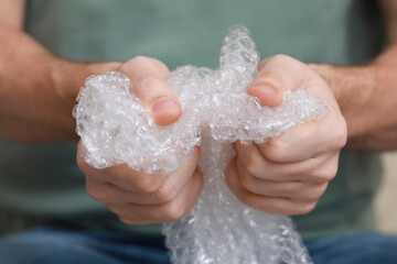 Man popping bubble wrap, closeup view. Stress relief