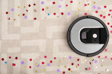 Wall Mural - Modern robotic vacuum cleaner removing confetti from carpet, top view. Space for text