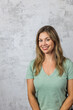© Ursula Page - An attractive brunette woman in her forties wearing a green t-shirt against a gray background