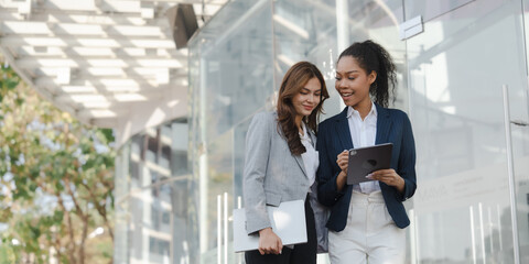 Two asia business women in conversation walking together on city street. Corporate colleagues workmate discussing new project while going to work. business outdoor.