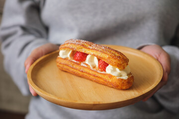 Wall Mural - Closeup image of a woman holding a plate of strawberry Eclair