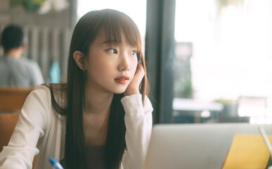 Wall Mural - Portrait of young adult asian student woman using laptop at cafe for study and work