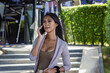 Sexy Asian business woman talking on mobile by office building outdoors. Young transgender person having phone conversation in urban city. Wireless communication concept
