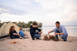 © Andrii Lysenko - Party, Camping of family with children, relaxing and firewood in campfire near tent on the sea shore